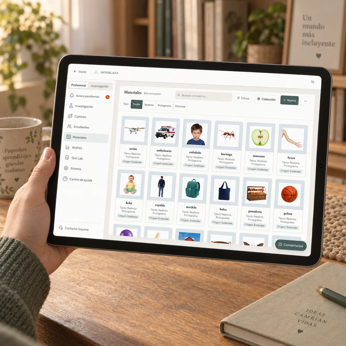 Una tablet sostenida con una mano muestra la biblioteca de Interlaza: el panel de filtros a la izquierda y una rejilla de tarjetas de concepto con fotografías